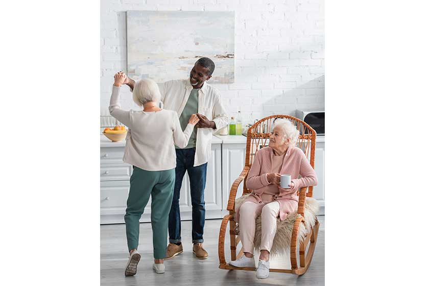 Positive multiethnic pensioners dancing near senior friend 