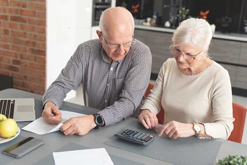 Senior couple paying bills together on laptop