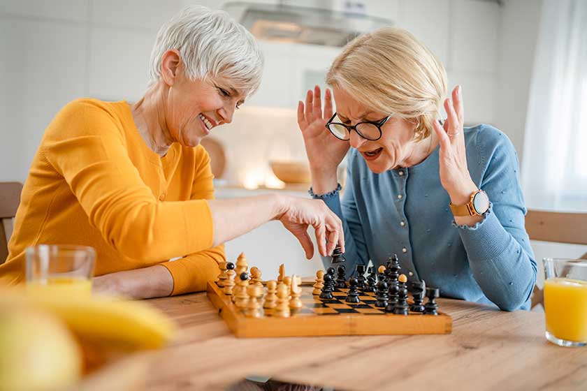 Two senior mature women caucasian female woman friend Playing Chess